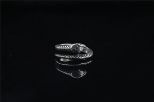 Macro shot of silver snake ring detail with realistic scale texture on black mirror base
