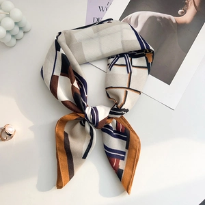 Detail of silk-texture square scarf tied in a bow with geometric patterns and soft drape