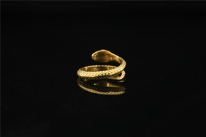Macro shot of gold snake ring featuring detailed scale engraving on black reflective background