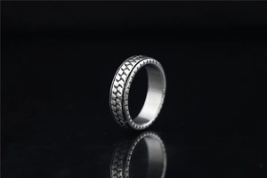 Detailaufnahme eines Edelstahlrings im Punk-Stil mit industrieller Reifenprofil-Textur