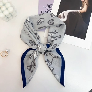 Detail of light grey square scarf with graffiti patterns and elegant knotted styling