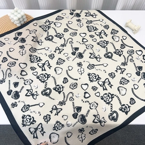 Close-up of elegant beige square scarf with black floral patterns and vintage motifs
