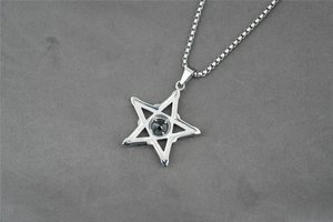 Macro detail of pentagram star pendant with black faceted gemstone on a steel box chain