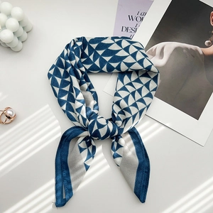 Dettaglio del foulard in seta blu e bianco con motivo geometrico e nodo decorativo raffinato