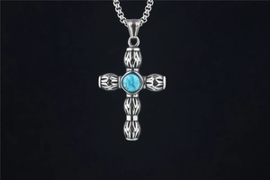 Gros plan du pendentif croix vintage avec incrustation de turquoise et gravures