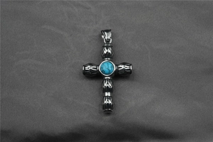 Détail du pendentif croix en acier vintage avec incrustation de turquoise sur tissu texturé