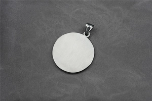 Close-up of a silver circular pendant made of polished titanium steel with metal buckle