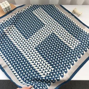 Dettaglio del foulard in seta con motivo geometrico blu navy e bordo grigio rifinito