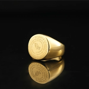 Golden signet ring with engraved Serenity Prayer and praying hands icon on black background
