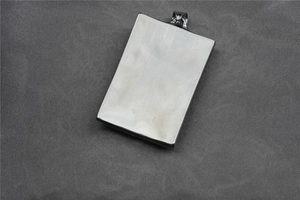 Détail macro d'un pendentif rectangulaire en acier avec motif tissé et tête de mort