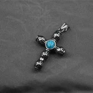 Pendentif croix vintage en acier oxydé avec pierre turquoise sur tissu texturé sombre