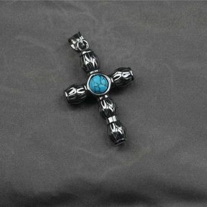Pendentif croix vintage en acier avec pierre turquoise sur fond de tissu gris