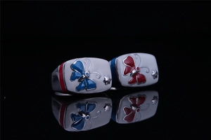 Gros plan sur des bagues en émail papillon avec motifs rouges et bleus en acier inoxydable