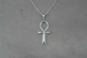 Dettaglio della collana con croce egizia Ankh in acciaio inossidabile su tessuto grigio