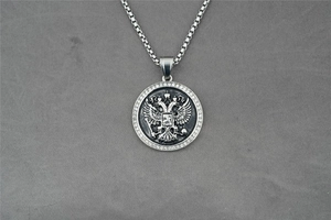 Détail du pendentif rond argenté avec aigle à deux têtes et zircons cubiques sertis