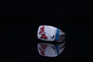 Détail de bague rétro en acier avec émail blanc, motif papillon rouge et insert bleu
