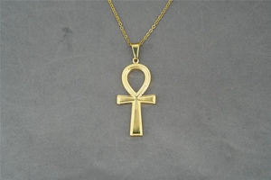 Dettaglio della collana con pendente a croce Ankh dorata lucida su sfondo grigio
