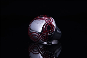 Detailed close-up of irregular stainless steel ring with red tribal line patterns