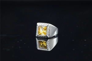 Macro-opname van zilveren titanium ring met vierkante gele edelsteen en Grieks patroon