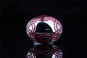Macro detail of silver stainless steel ring with red Celtic enamel patterns