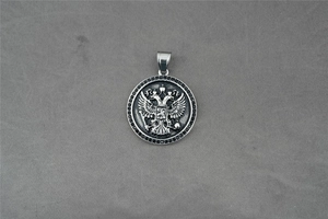 Vue détaillée du pendentif rond argenté avec blason d'aigle et bordure noire sertie