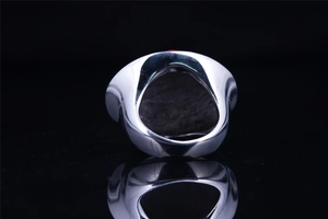 Detailed macro view of the irregular silver steel ring with red enamel and mirror reflection