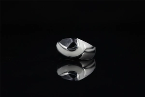 Detail of silver ring with black oval stone and white enamel waves on black mirror