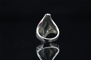 Macro view of vintage silver ring with red teardrop stone on reflective black background