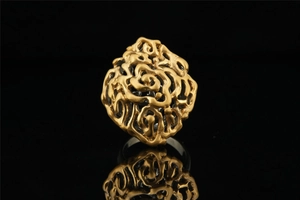 Macro shot of gold hollow ring featuring intricate walnut pattern with matte texture finish