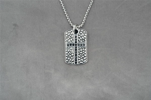 Makroaufnahme vom Hip-Hop-Anhänger mit schwarzem Kreuz und gehämmerter Metalloberfläche