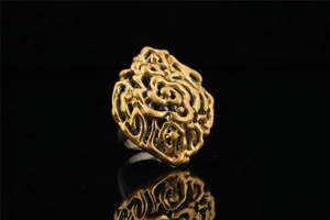 Macro shot of gold hollow-out floral pattern ring with elegant mirror reflection