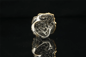 Macro shot of two-tone hollow geometric pattern titanium ring on reflective surface