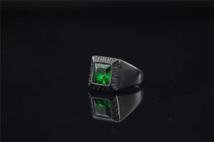 Macro-opname van groene edelsteen in zwarte titanium ring met Griekse gravering