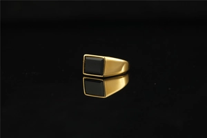 Macro detail of men's titanium ring with rectangular black gemstone on dark mirror