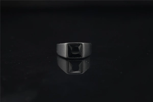 Macro shot of matte black signet ring featuring a square cut gemstone with reflection