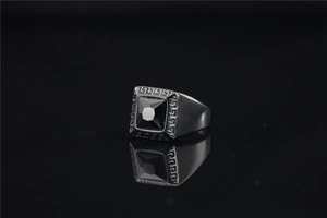 Macro-opname van roestvrijstalen ring met zwarte edelsteen en Grieks sleutelpatroon detail