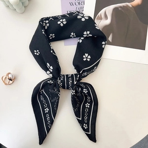Close-up of black and white clover print square scarf tied in a silk-textured bow