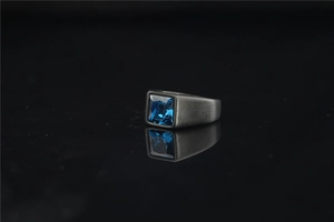 Macro shot of men's wide titanium steel ring with blue square gemstone and brushed finish