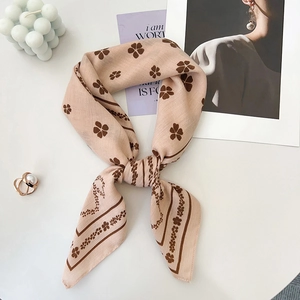 Macro detail of French retro silk-feel scarf with brown clover pattern on soft pink base