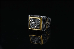 Detail of square signet ring featuring golden skull wings and inlaid dark zircons