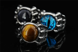 Macro shot of gothic dragon claw rings featuring a brown tiger eye stone and blue evil eye
