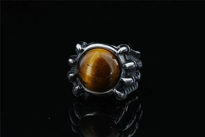 Close-up of retro dragon claw ring holding a round tiger eye stone in stainless steel