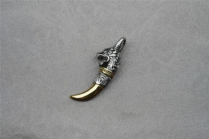 Detailed view of punk style bicolour wolf head and tusk pendant on grey fabric
