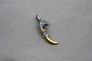 Detail of vintage wolf head pendant with gold tusks and textured silver finish