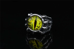 Macro shot of gothic dragon claw ring with a yellow evil eye on black reflective background