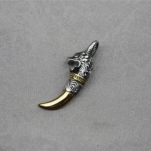 Vintage silver wolf head pendant with golden fang detail on grey textured background