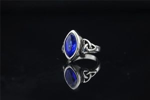 Détail macro d'une pierre bleue de taille marquise et gravures celtiques sur la bague