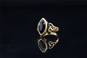 Détail macro de la bague nœud celtique dorée ornée d'une grande pierre noire taille marquise