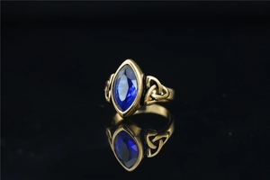 Détail d'une bague vintage dorée avec pierre bleue marquise et motifs nœuds celtiques