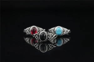 Detail of vintage turquoise rings with hollow woven texture on a black mirror surface